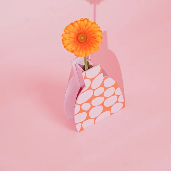 Drewniany wazon dekoracyjny w śmiałych różowo-pomarańczowych kolorach. 